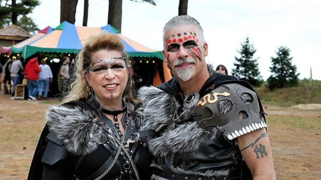 Couple dressed in Viking-inspired costumes with fur, face paint, and leather armor at outdoor festival.